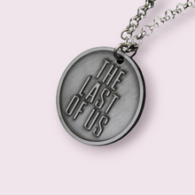 Load image into Gallery viewer, This stunning necklace is sure to delight any fans of the Last of Us game and / or series. Depicting the firefly symbol on the one side and &quot;The Last of Us&quot; on the other. Size roughly 3.2cm, material zinc alloy
