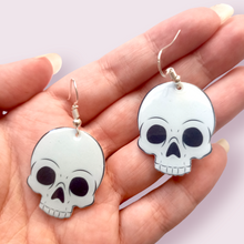 Load image into Gallery viewer, How cute are these little skulls? These stunning earrings are designed and made in-house and are also available in grey. Material: shrink film, resin, nickel free hooks. Please note as these are all handmade, minor differences may occur from piece to piece.  All shrink film products can take about a week to send out as they are currently made to order
