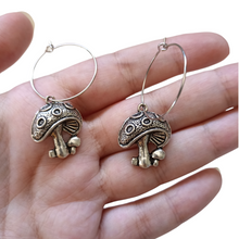 Load image into Gallery viewer, These adorable mushroom earrings would make an amazing gift for those drawn to nature, spirituality or the cottage core aesthetic. Pendant Size Roughly 2cm, hoop size roughly 2.4cm. Material: zinc alloy. Locally sourced and handmade by The Raven’s Claw. 
